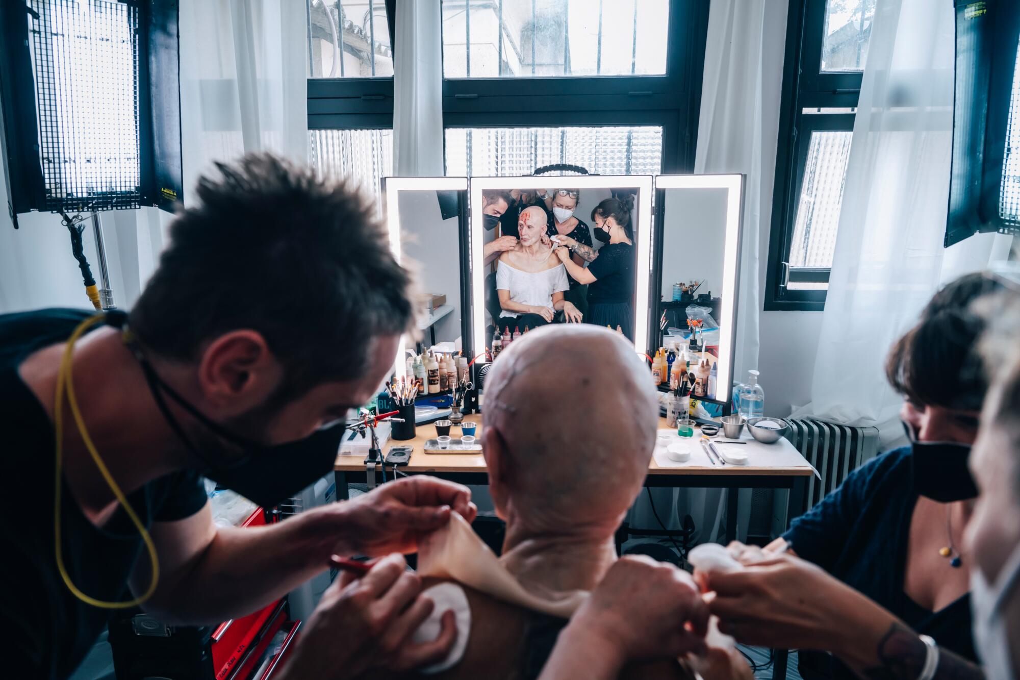 Demi Moore is seen in a mirror as makeup artists apply her deteriorating look for 