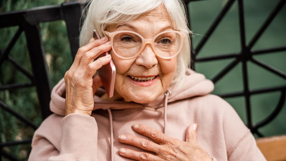 Joyful old lady talking on cell phone outdoors stock photo