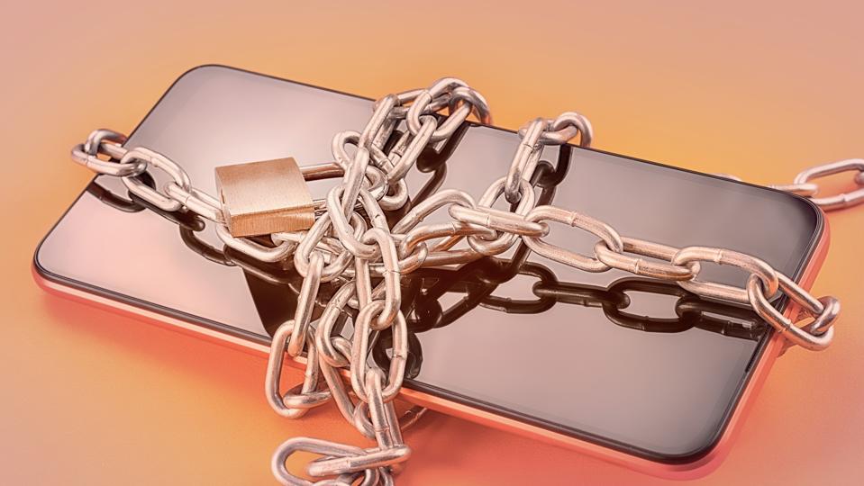 Smart phone in chain with lock on orange background with selective focus