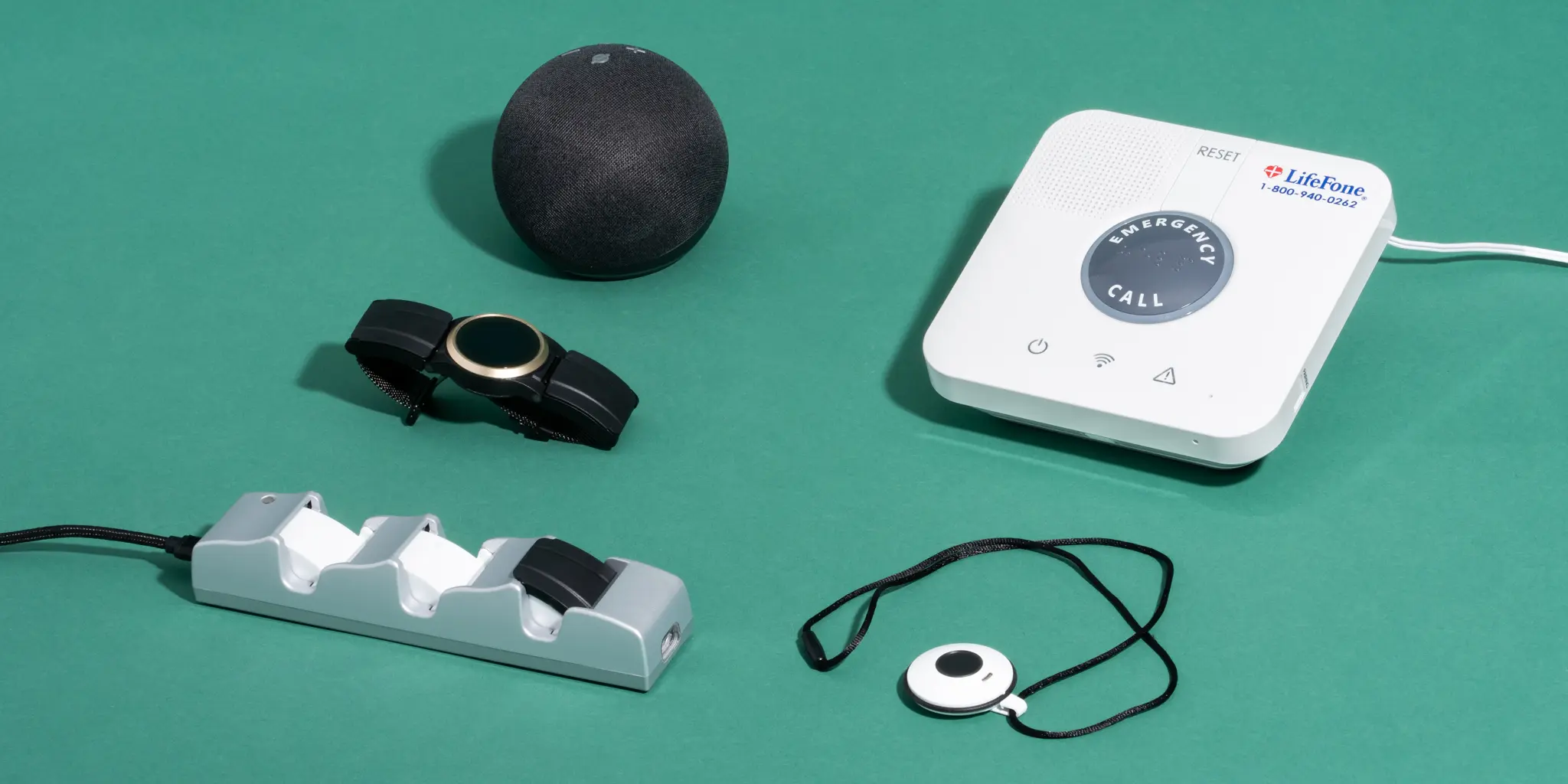 A collection of four medical alert devices, and the battery charger for one of them, displayed together.