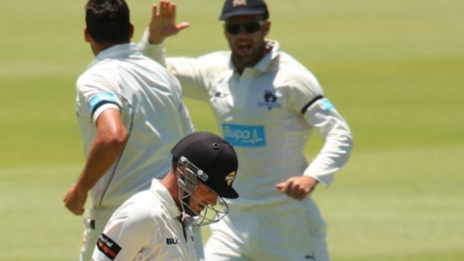 Shaun Marsh walks back to the rooms as Scott Boland and Rob Quiney celebrate his dismissal.