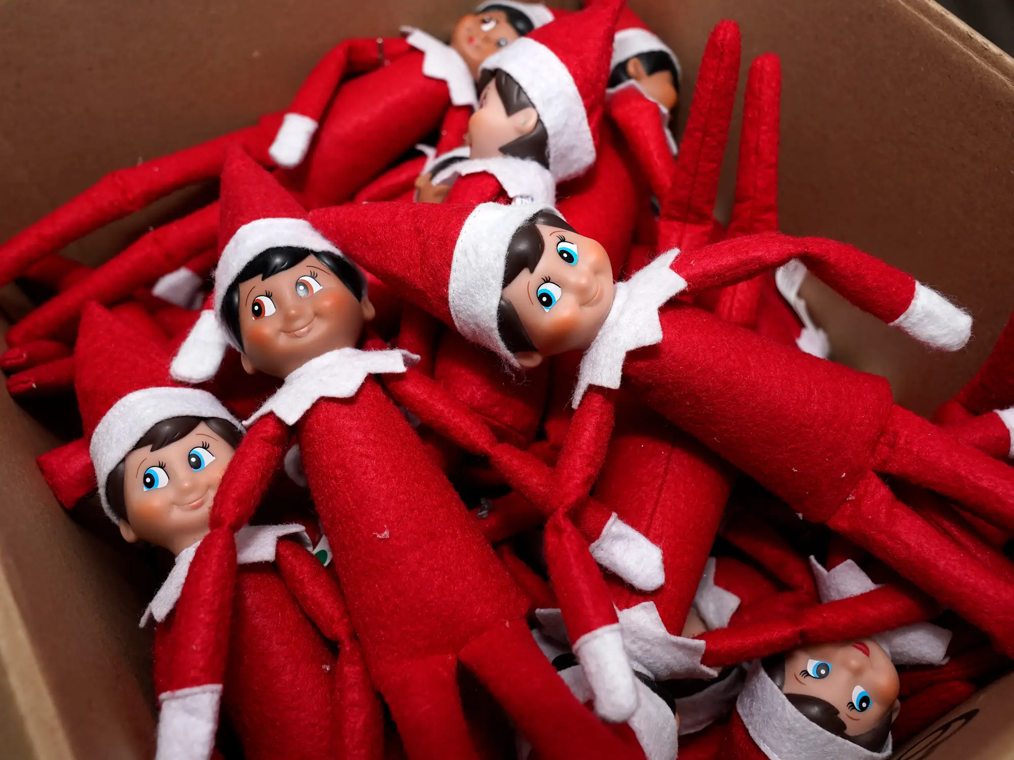 Elf on the Shelf figures are piled in a box