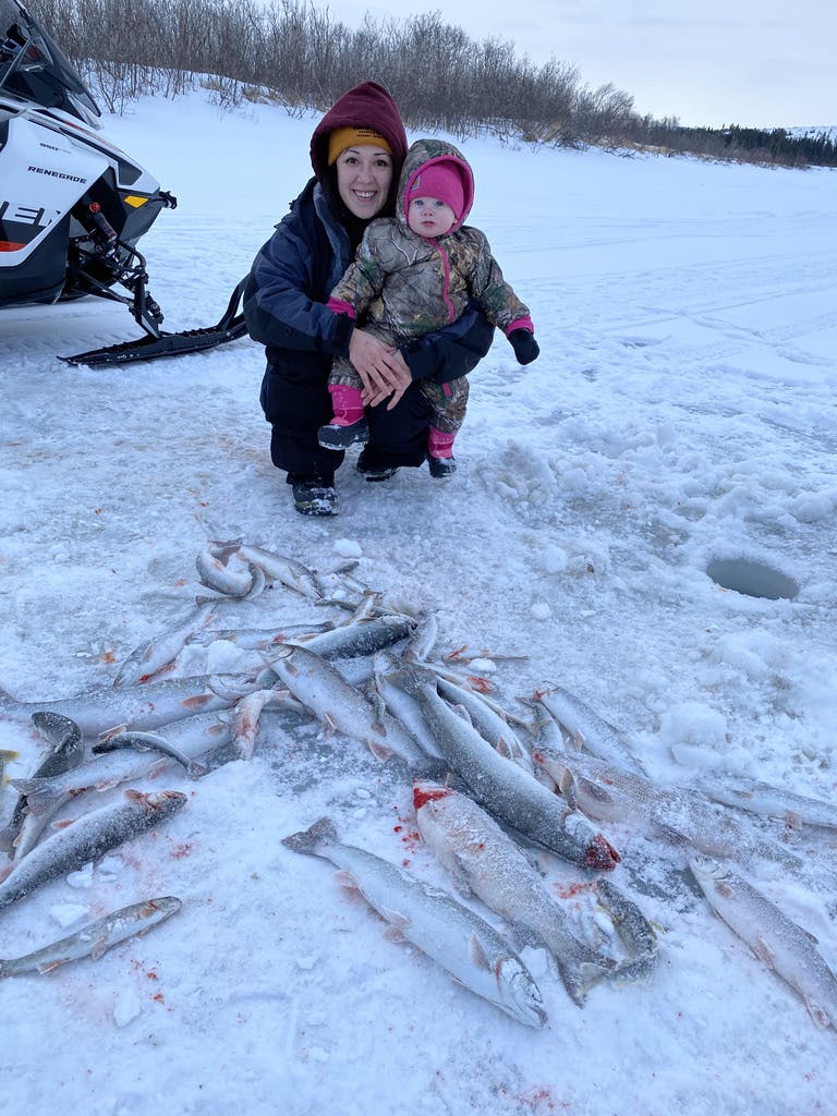 Inupiaq mother Kelsi Ivanoff and daughter Harlow Ralphie, with Dolly Varden trout, whitefish and grayling caught ice fishing in the Unalakleet River a few miles upriver from Unalakleet, Alaska. (Photo courtesy of Steve Ivanoff)