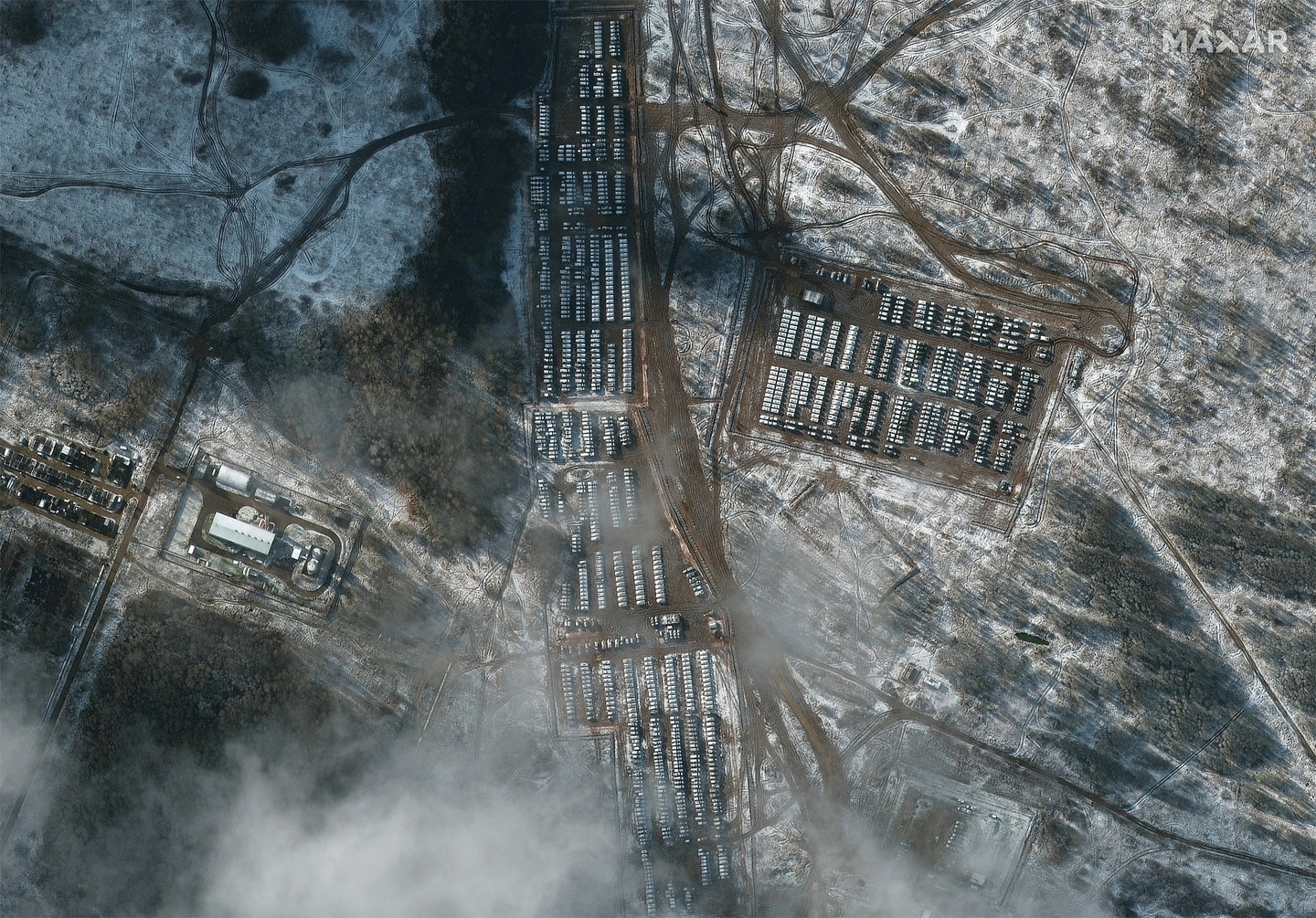 Bird's eye view of hundreds of vehicles deployed in a snowy landscape.