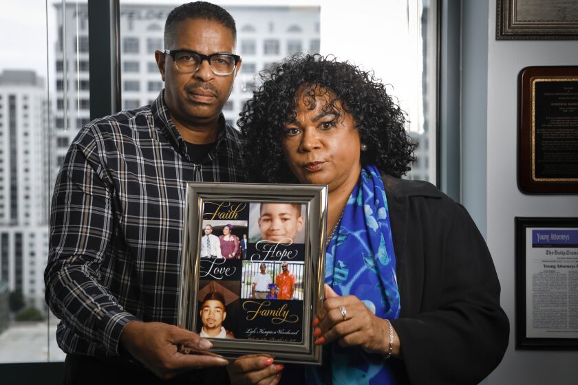 Edward Woodward, left, and his wife, Bessie Woodward, right, hold a framed photo collage of their son, Lyle Woodward, June 26, 2019 in San Diego, California who died while in San Diego County Jail.