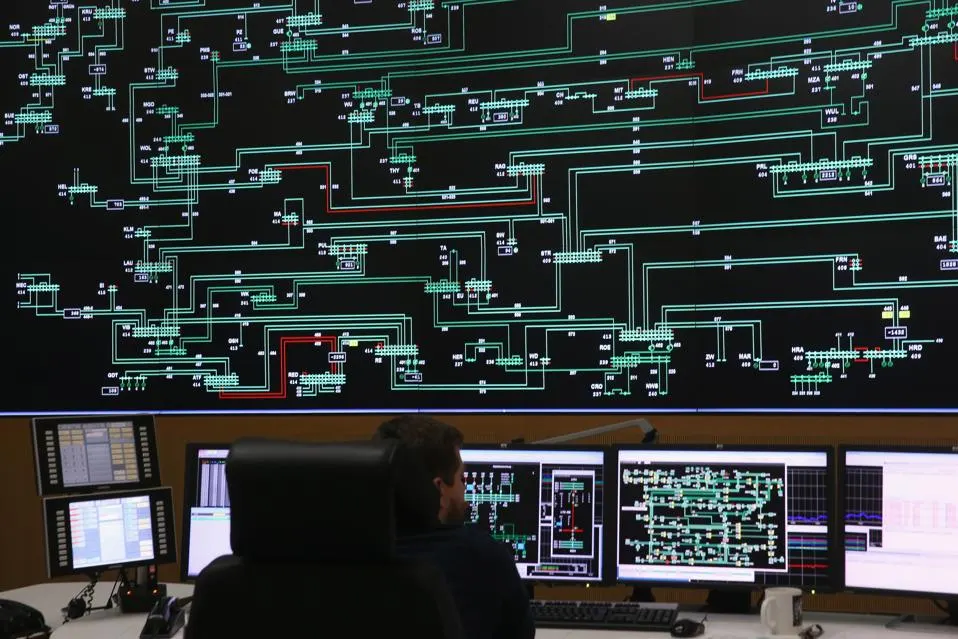 NEUENHAGEN BEI BERLIN, GERMANY - DECEMBER 17: A technician monitors electricity levels in front of a giant screen showing the eastern German electricity transmission grid in the control center of grid operator 50 Hertz on December 17, 2015 in Neuenhagen bei Berlin, Germany.