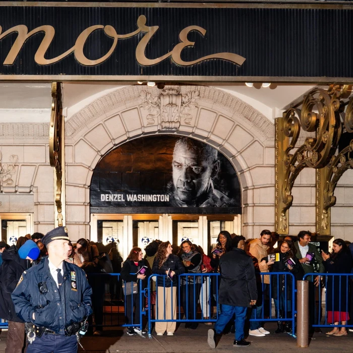 People lined up outside a theater under a Denzel Washington poster