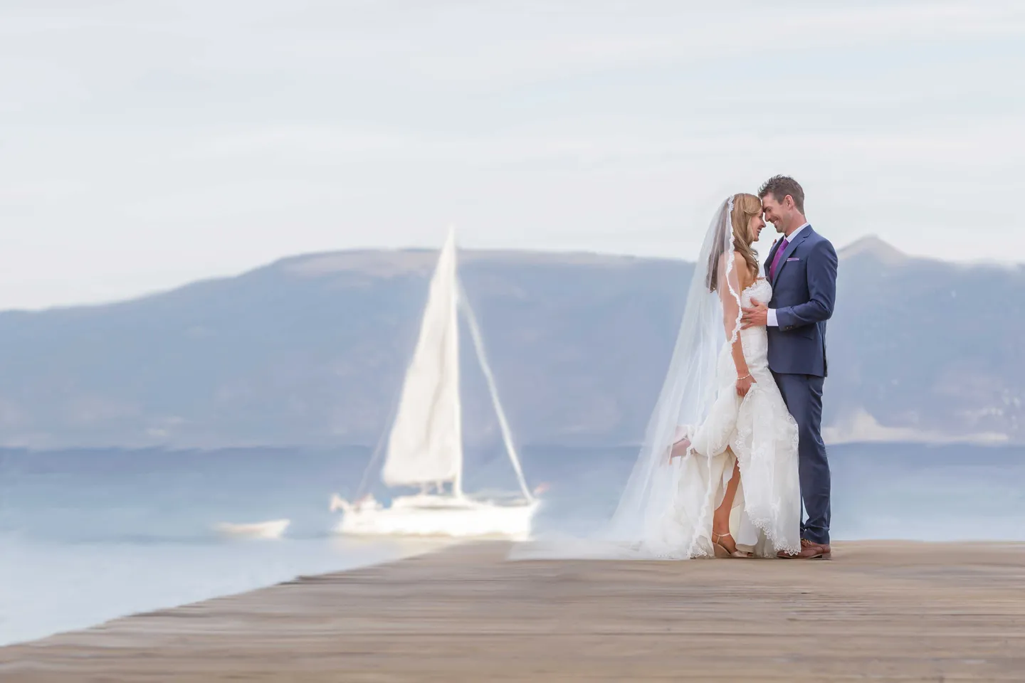 bride-groom-pose-dock-lake-tahoe-sailboat-long-veil-blue-suit-purple-tie