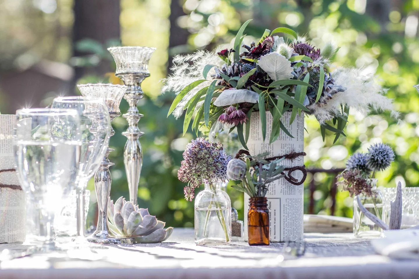 wildflower-centerpieces-wildflowers-in-bookpages-and-small-bottles-silver-candlesticks