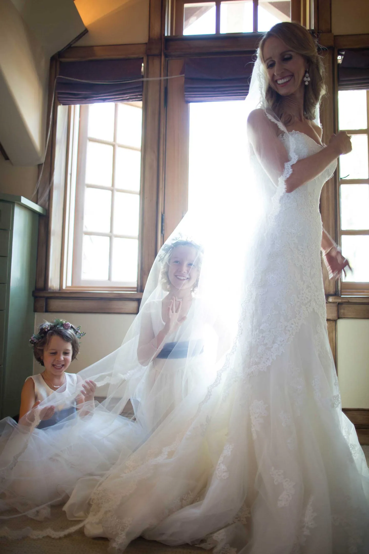 flower-girls-play-under-brides-veil-bride-smiling-flower-crowns-sash-dresses
