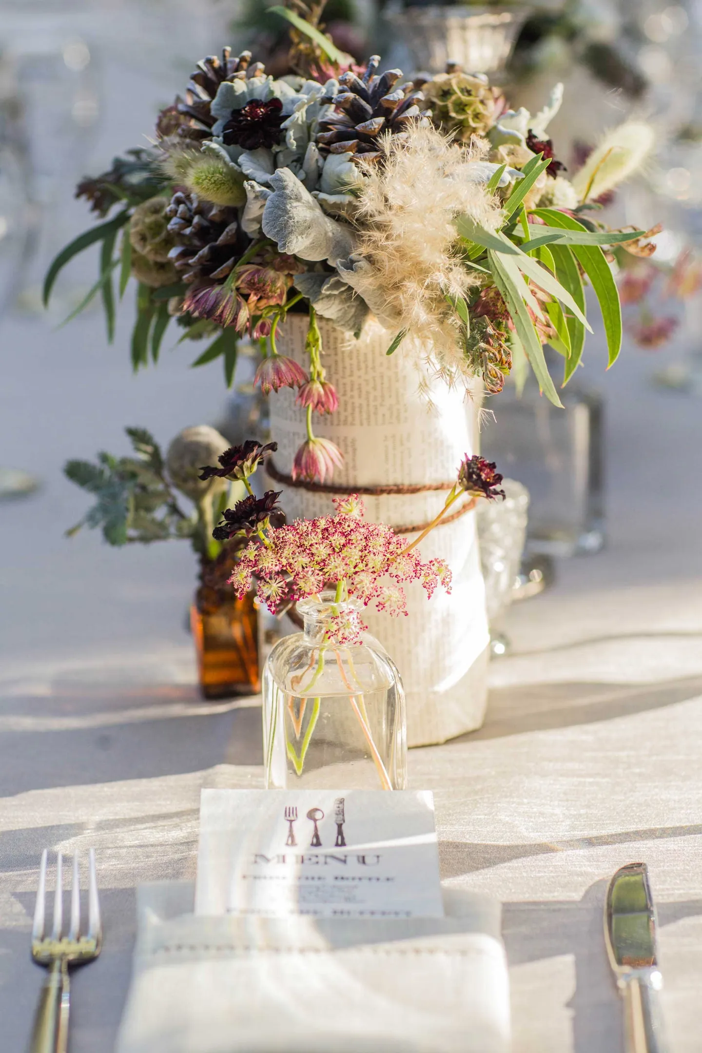 wildflower-and-pinecone-centerpieces-wrapped-on-book-pages-tied-in-twine