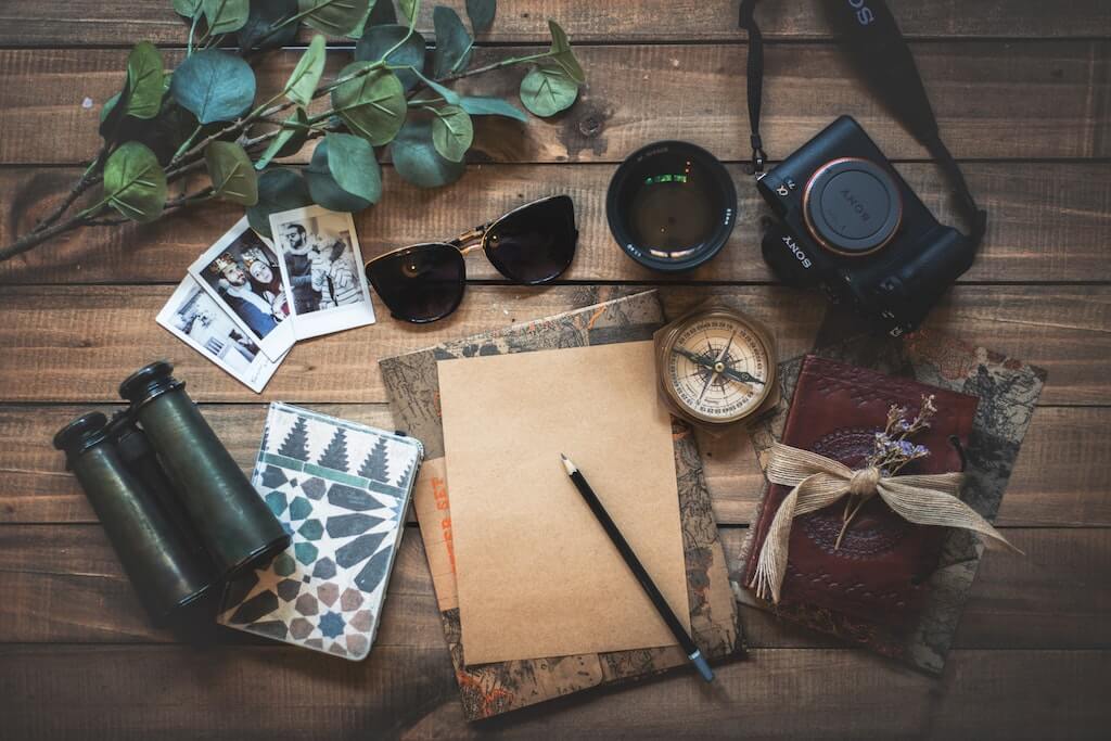 travel and mental health jet set items sunglasses binoculars adventures camera notebook compass photos wanderlust