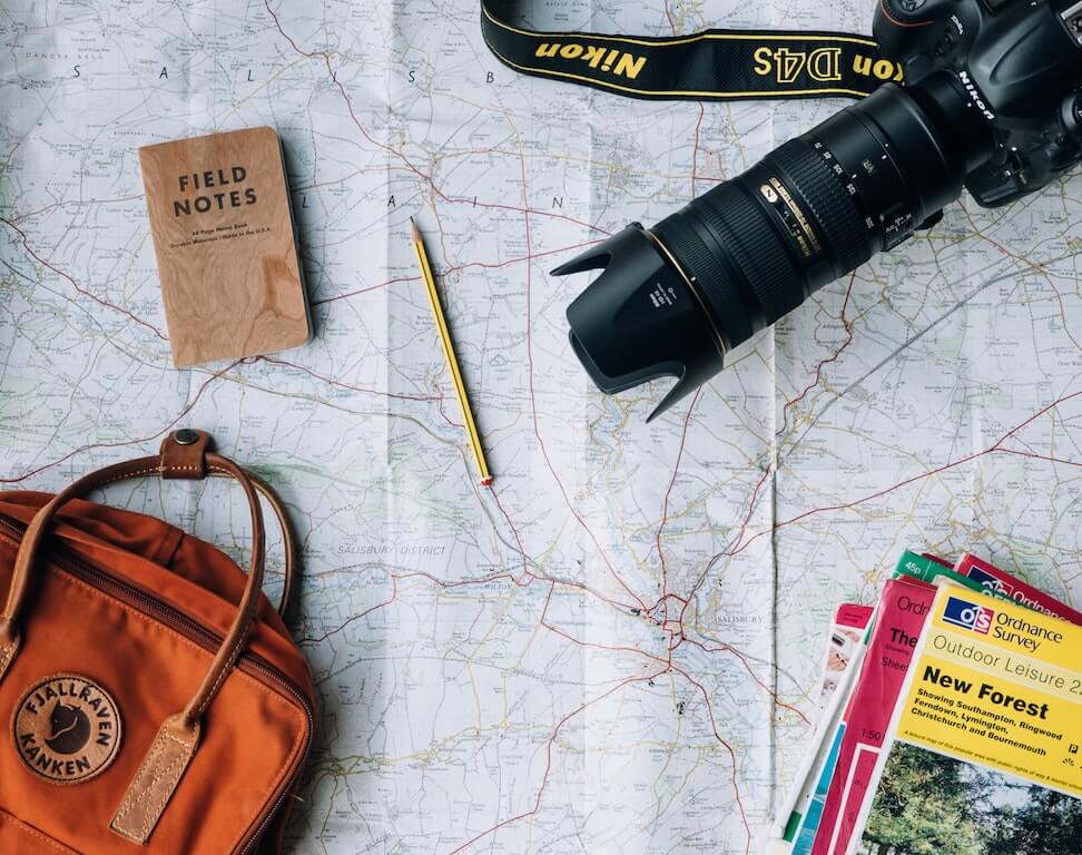 travel and mental health plane fly wanderlust items field notes notebook camera map guide books purse