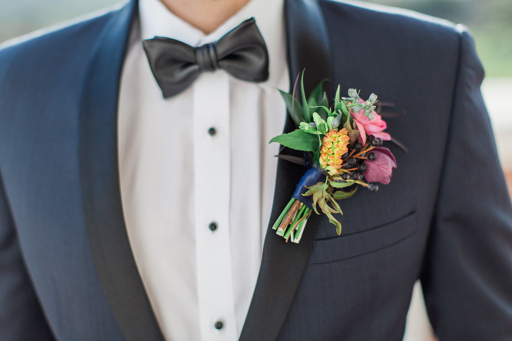 Boutonniere with pink and orange flowers navy tuxedo jacket with black lapels