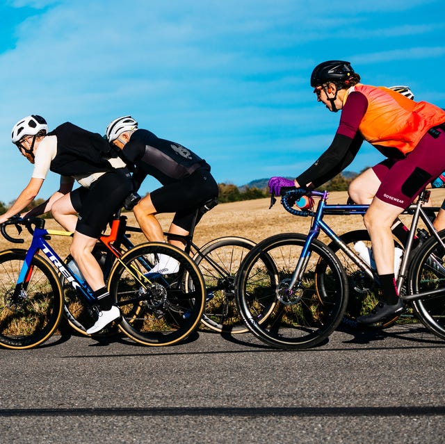 cyclists riding on a road in a rural setting with a field in the background