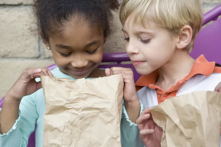 Two children looking in paper lunch bag