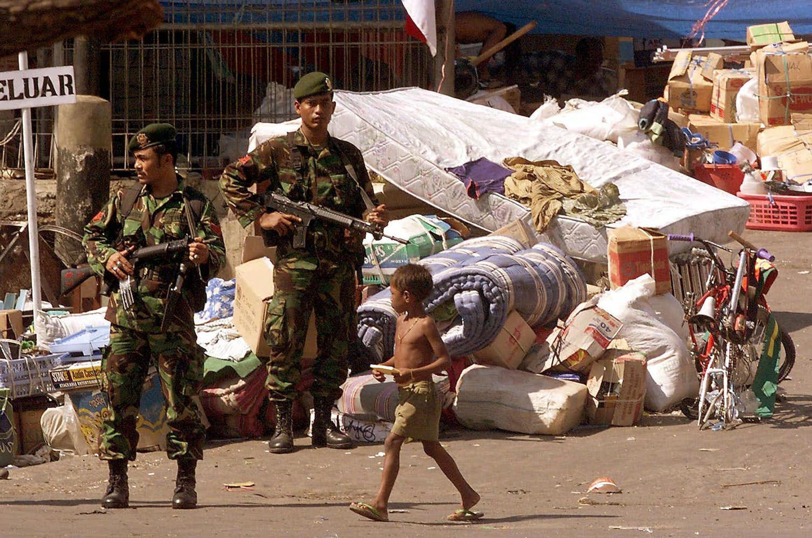 A Timorese child walks past Indonesian soldiers in Dili