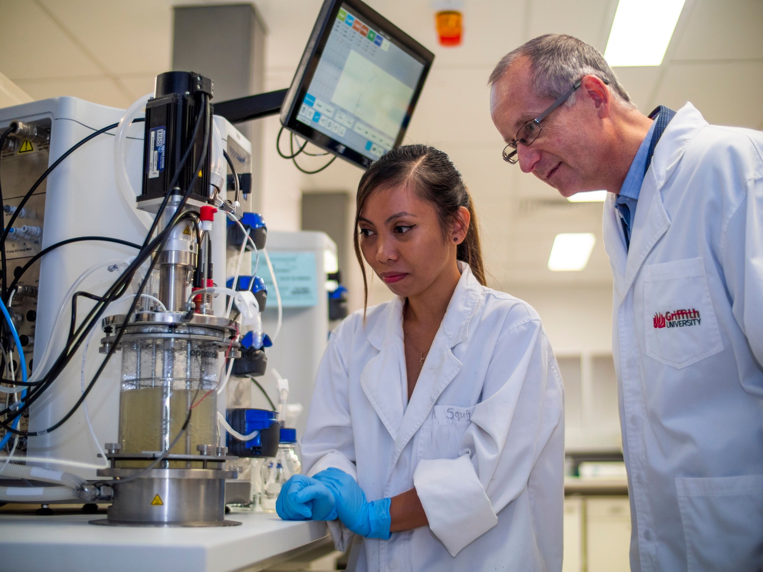 PhD student Zennia Jean Gonzaga and Prof Bernd Rehmwith to the bio-reactor which grows cell factories to make functional polymer particles [Griffith University]