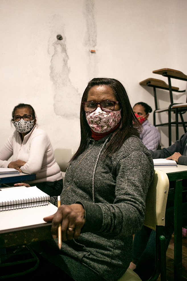 "Antes me falavam 'você é burra'. Mas ninguém é burro. Porque eu nunca vi um burro com um caderno e um lápis na mão." Maria Dolores da Silva, 67 anos, é aluna do Movimento de Alfabetização de Jovens e Adultos (MOVA), em Heliópolis, São Paulo."Agora eu consigo fazer as contas de casa para ver se o dinheiro dá. Eu faço e mostro para o meu filho pra ver se tá certo. Foi ela [professora Rita] que me convenceu a aprender. Foi bem na época da pandemia. Então ela ia até a minha casa, buscava os meus cadernos e passava lição." Foto: Rosana Pinheiro