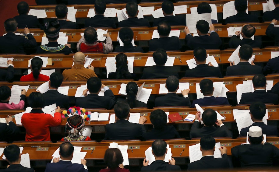 Delegates read work reports during a plenary session at the Great Hall of the People in Beijing on Tuesday.