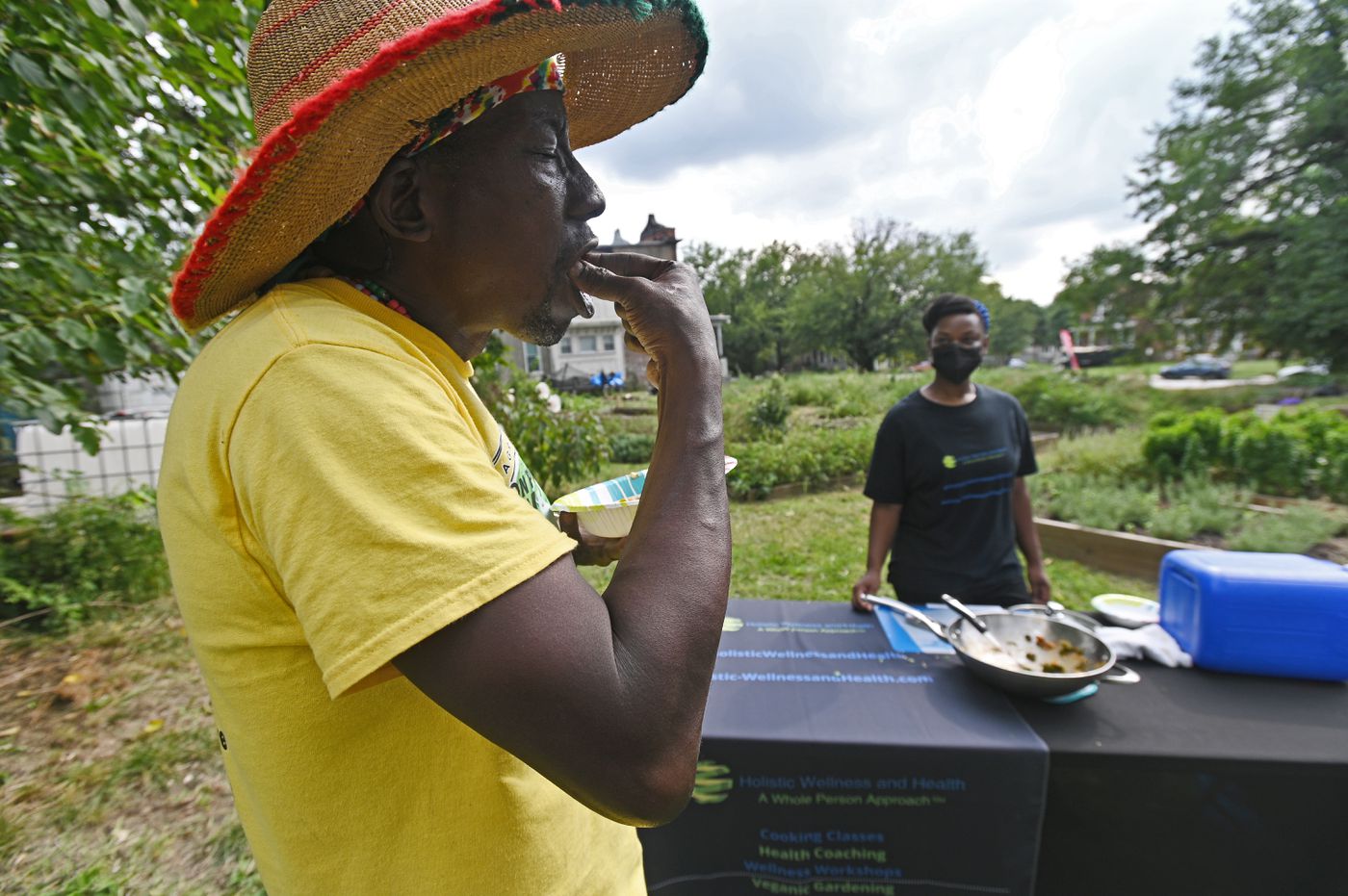 Plantation Park Heights Urban Farm founder Richard 'Farmer Chippy' Francis, left, of Trinidad, tastes vegetables cooked by Crystal Forman, right, using produces from a giveaway food boxes.