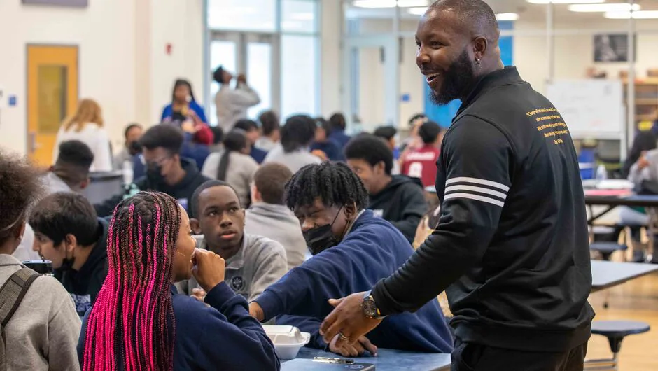 Teacher greets students and has lively conversation in the cafeteria.